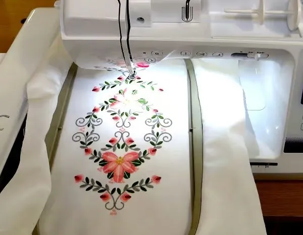 Máquina de bordar digital trabajando un motivo floral sobre tela blanca