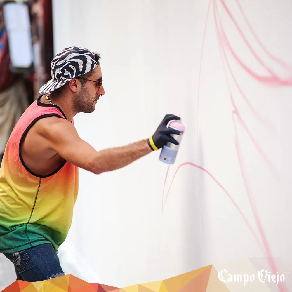 Artista pintando un mural con spray en un evento de marca