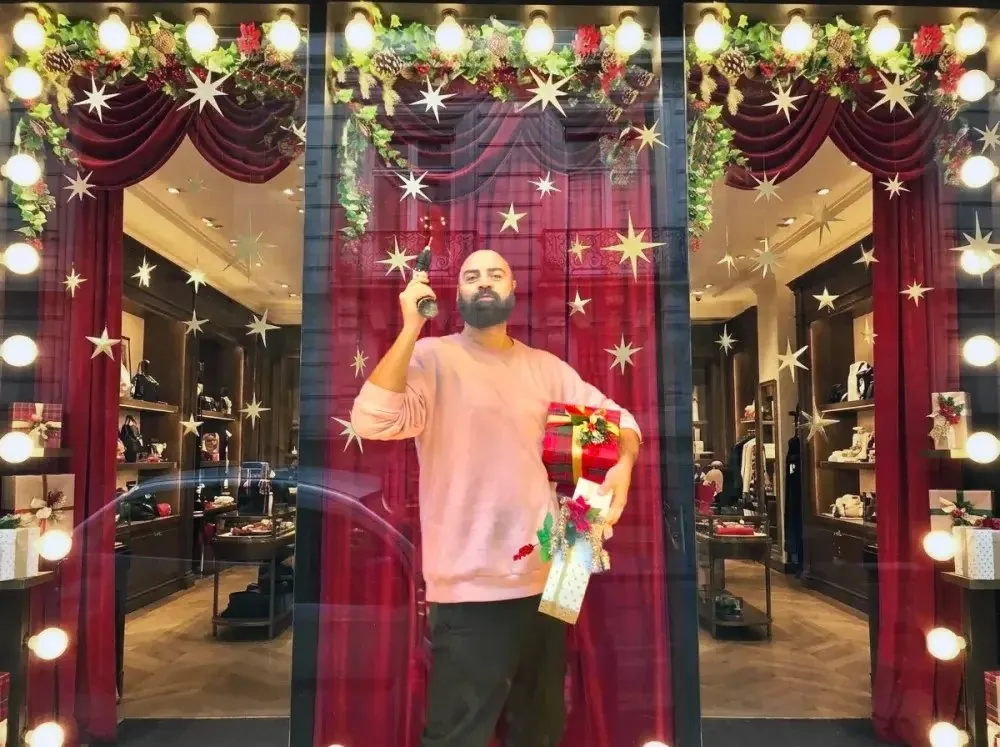 Escaparate navideño con cortinas granates, luces y estrellas, y un creativo en primer plano