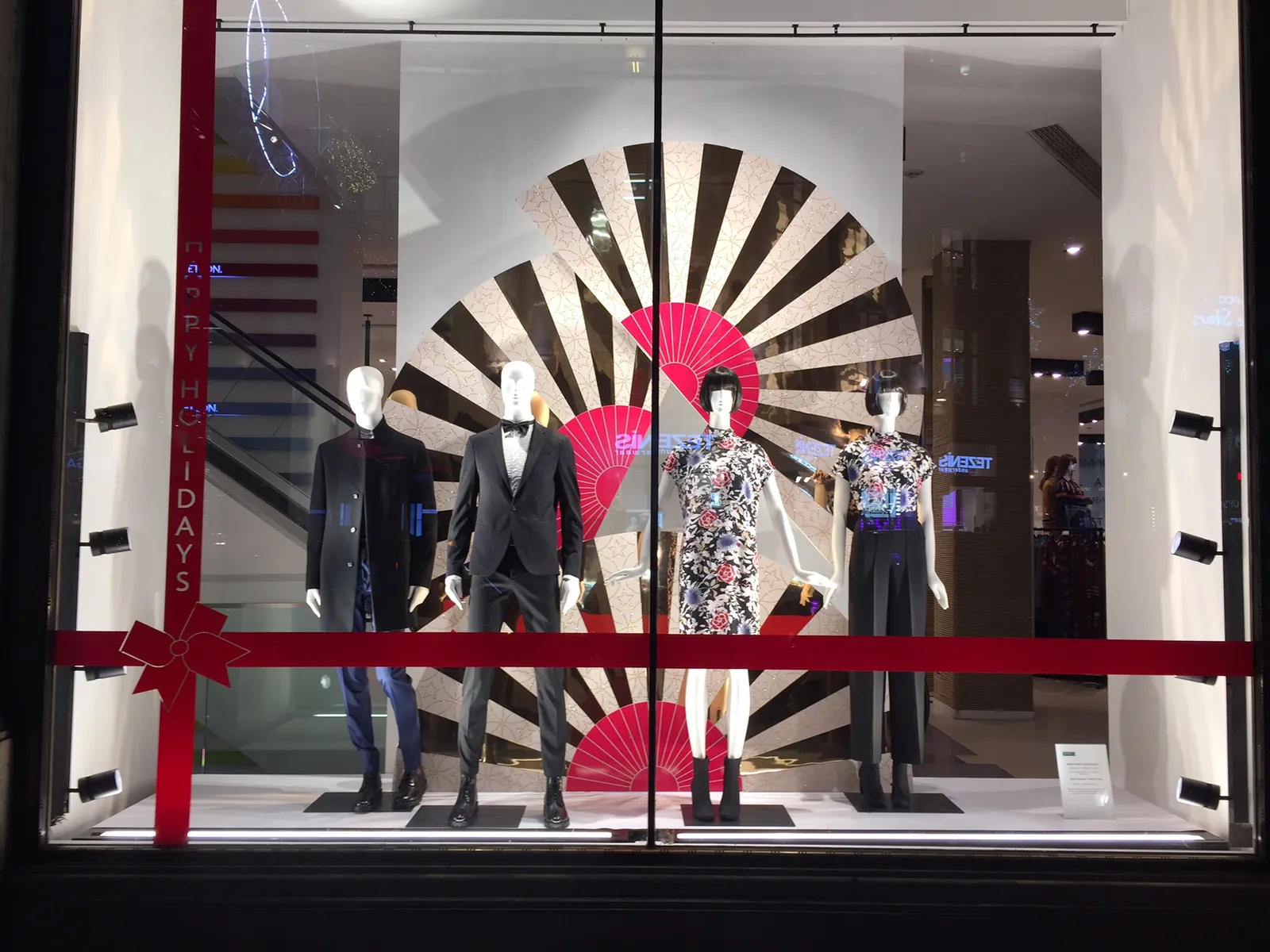 Escaparate de Navidad en Londres con un gran abanico rojo y maniquíes